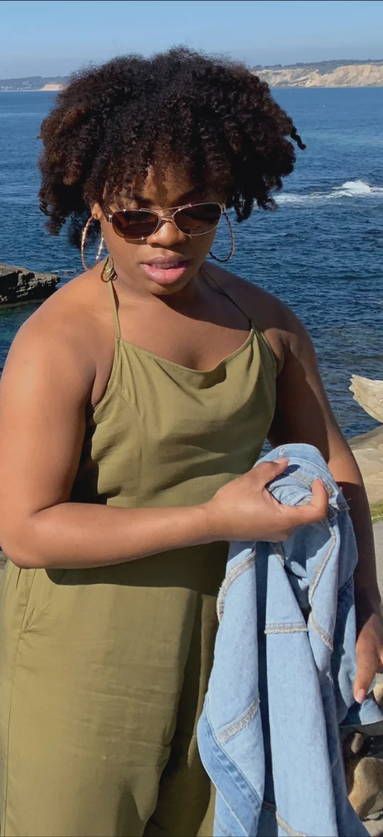 Michelle in her 20s, standing by the ocean